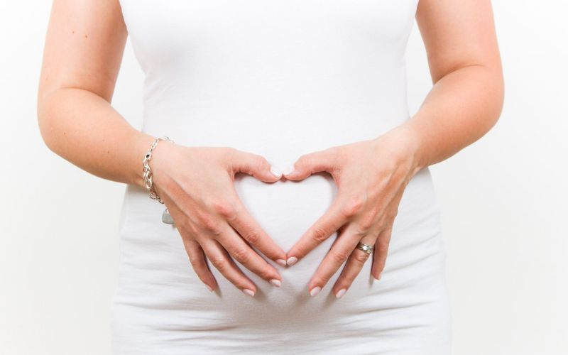 Schwangere Frau bildet ein Herz mit Ihrer Hand auf dem Bauch